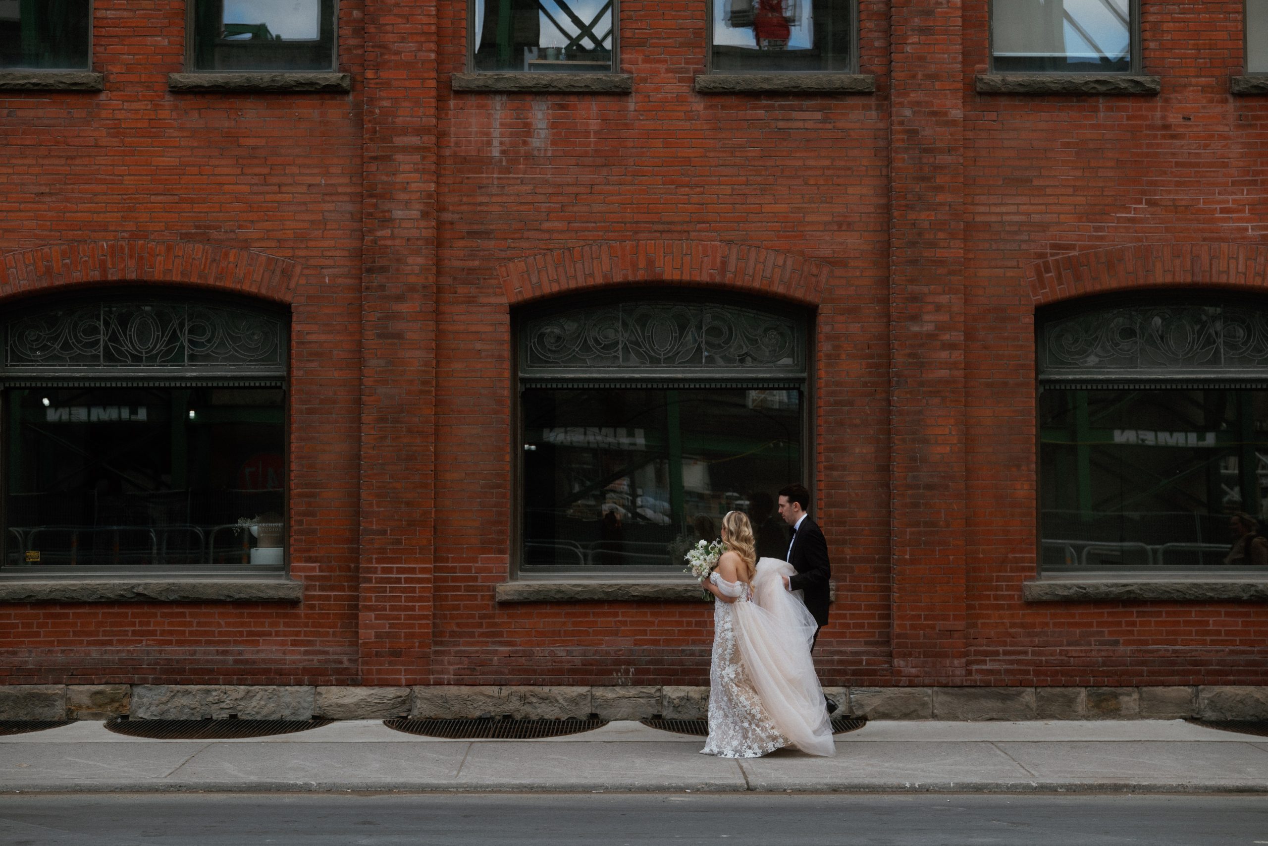 couple walks down Richmond Street in Toronto, with historic building behind them