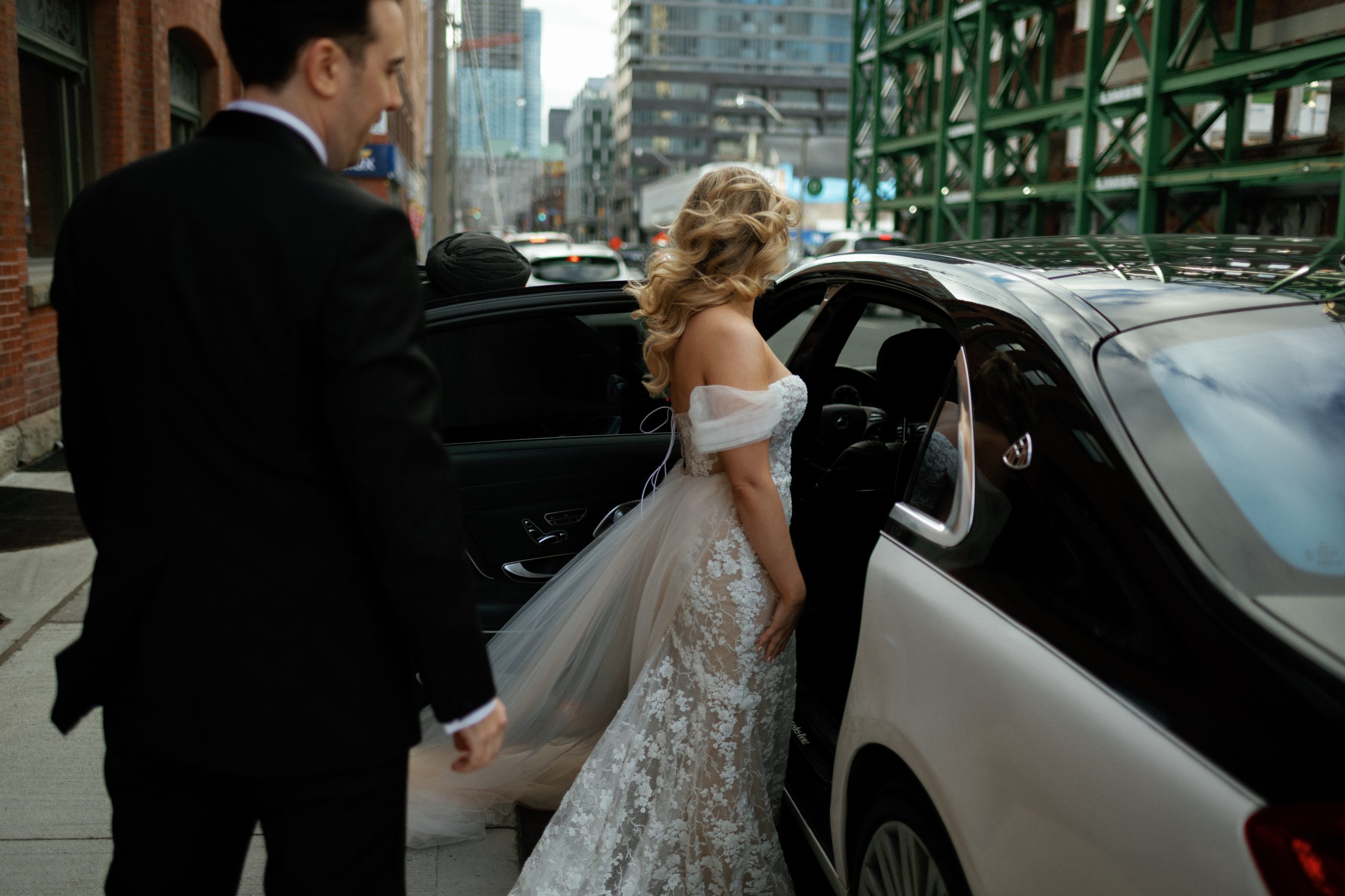 bride gets ready to enter vintage car on the way to the wedding reception
