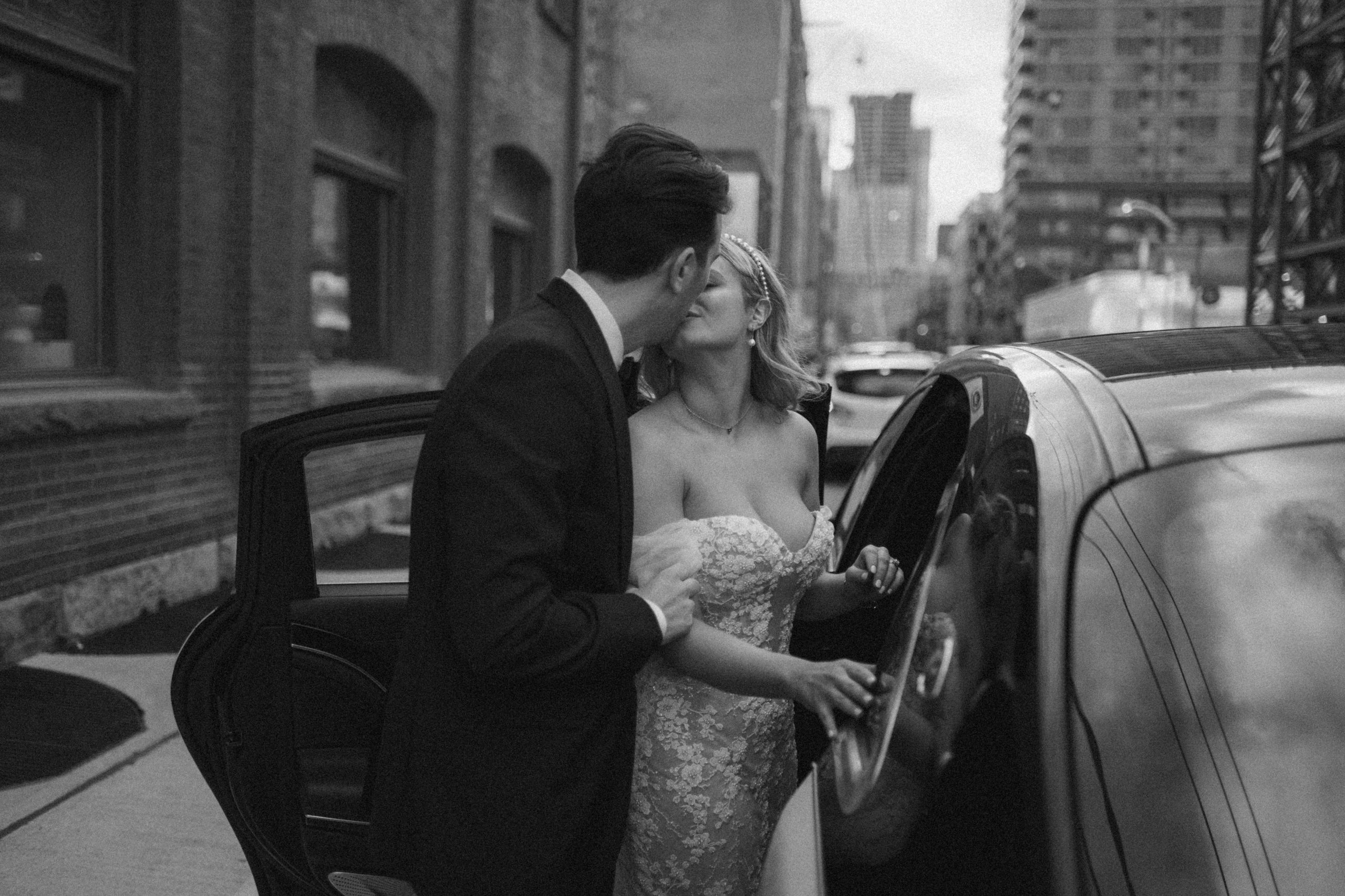 bride and groom share a kiss by the vintage car before they leave for the reception